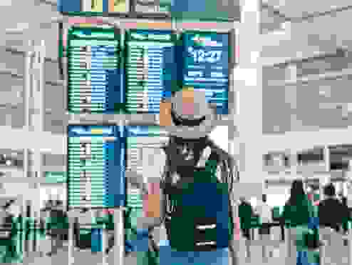 Women in a hat looking at her flight times  at the airport